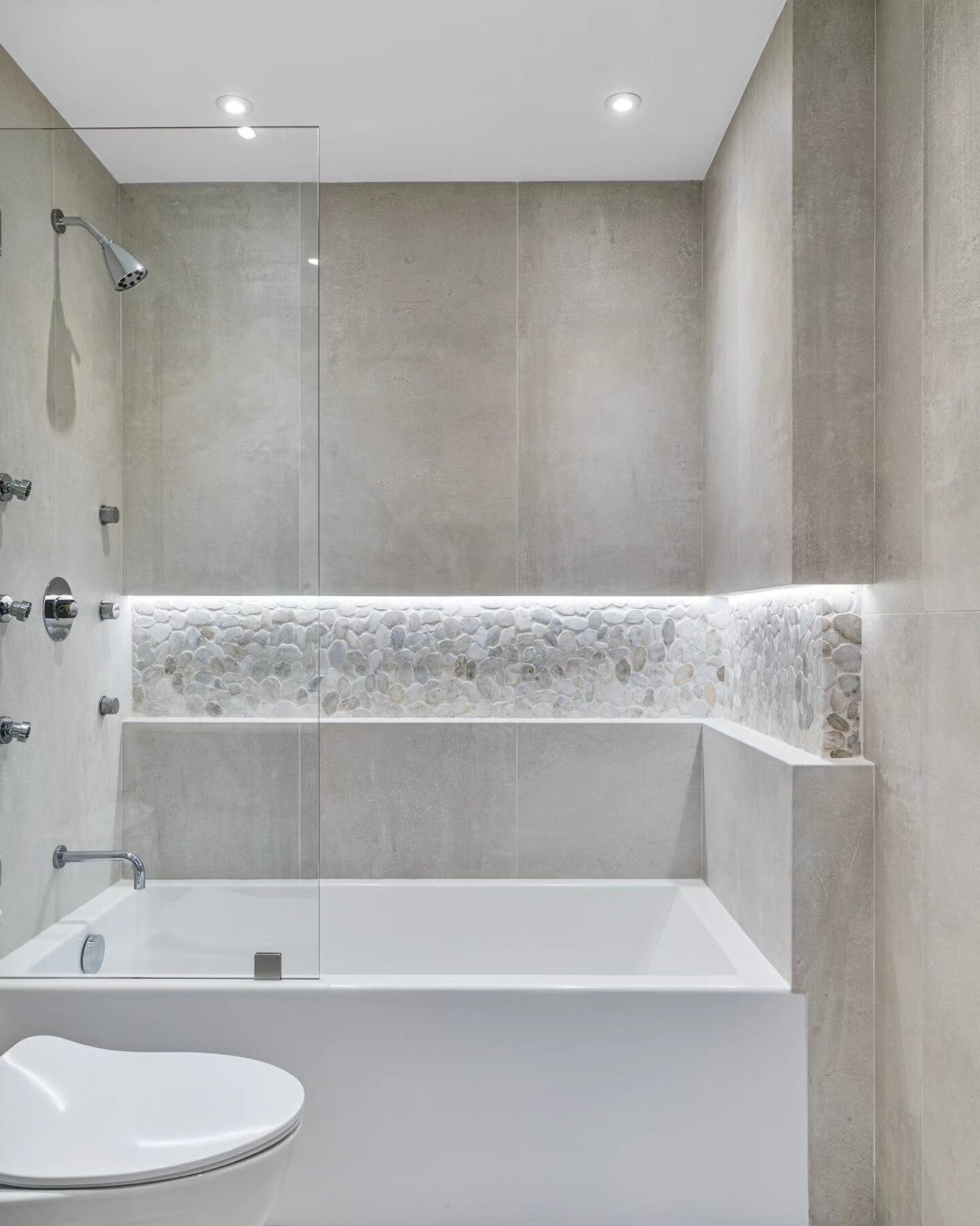 Spa bathroom with freestanding tub, large-format concrete-look tile and pebble accent niche, Williamsburg