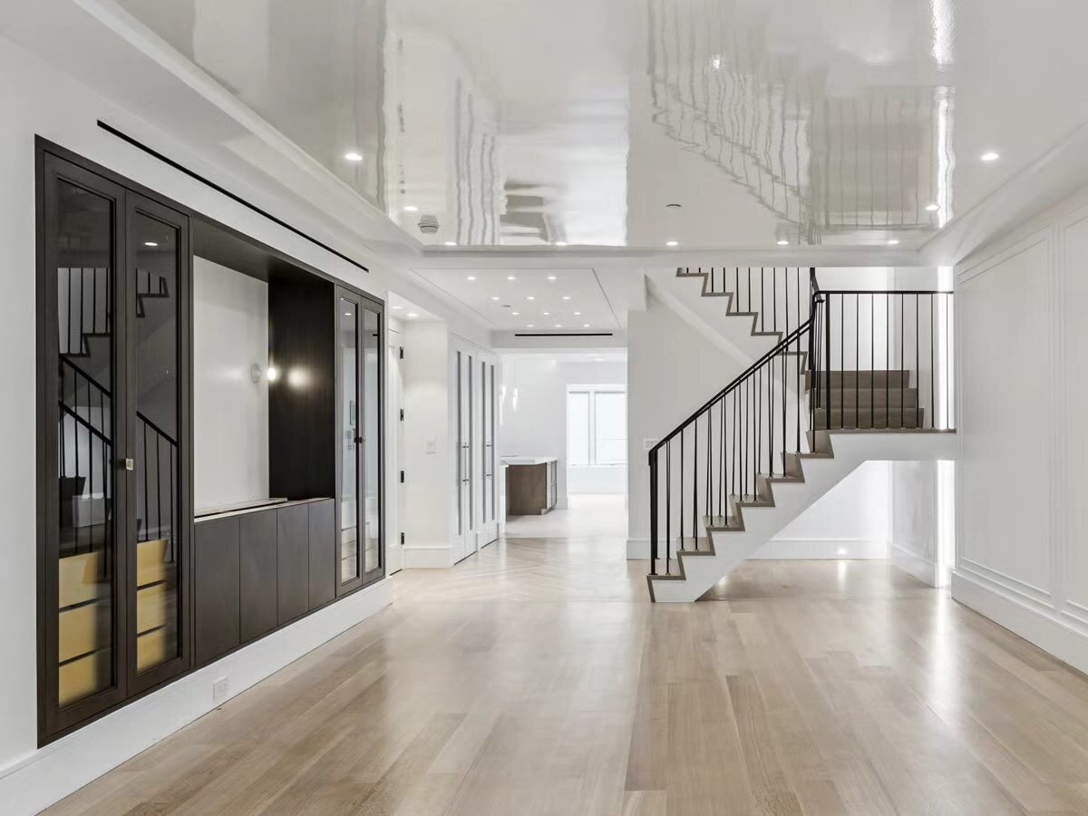 Open great room with white oak floors, black steel staircase and custom dark cabinetry in a Brooklyn home
