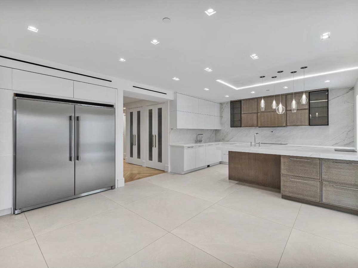 Large kitchen with two built-in refrigerators, marble backsplash and pendant lighting