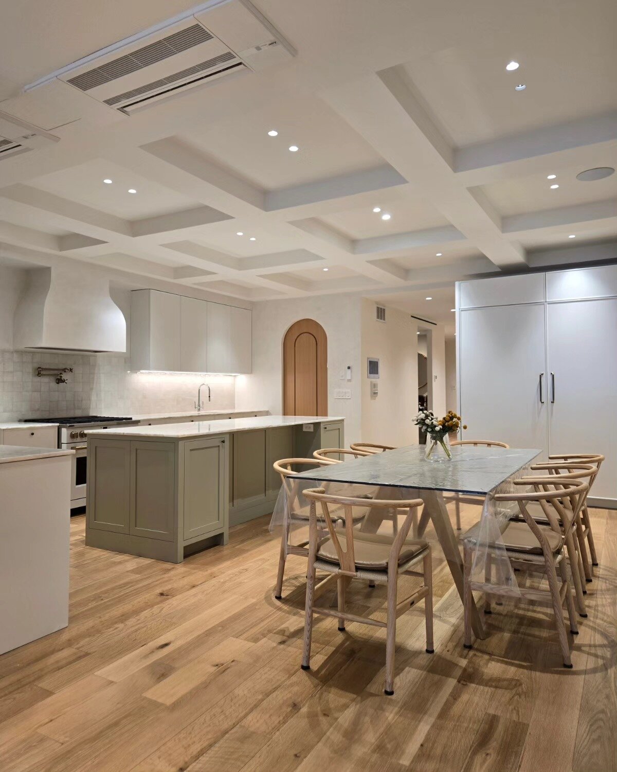 Kitchen and dining area with coffered ceiling, sage island and arched wood door, Brooklyn