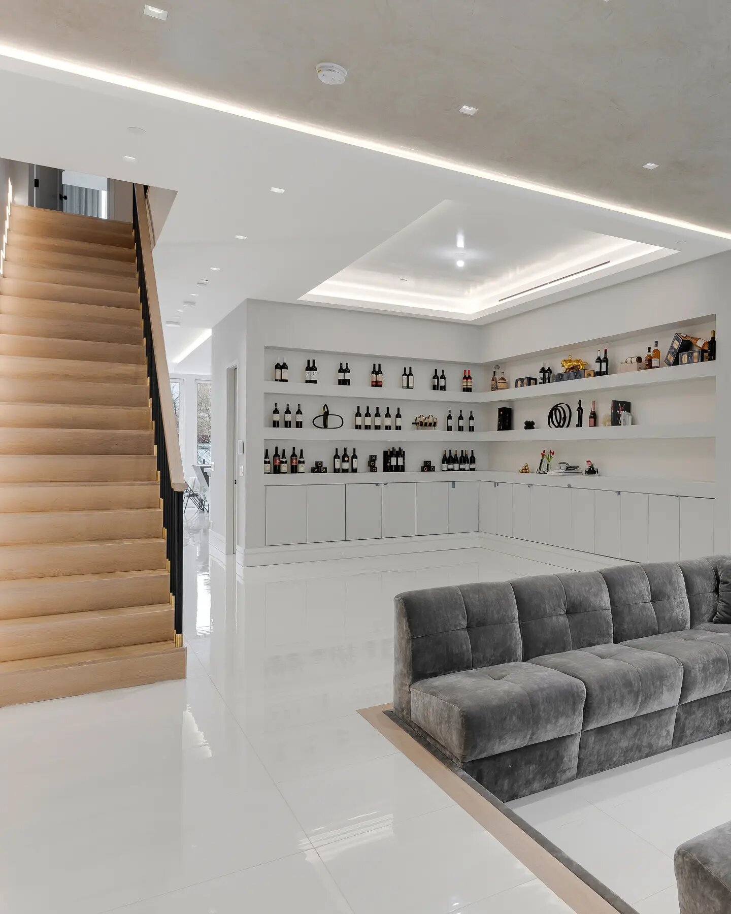 Bright lower-level lounge with bar shelving and white oak stairs, Brooklyn