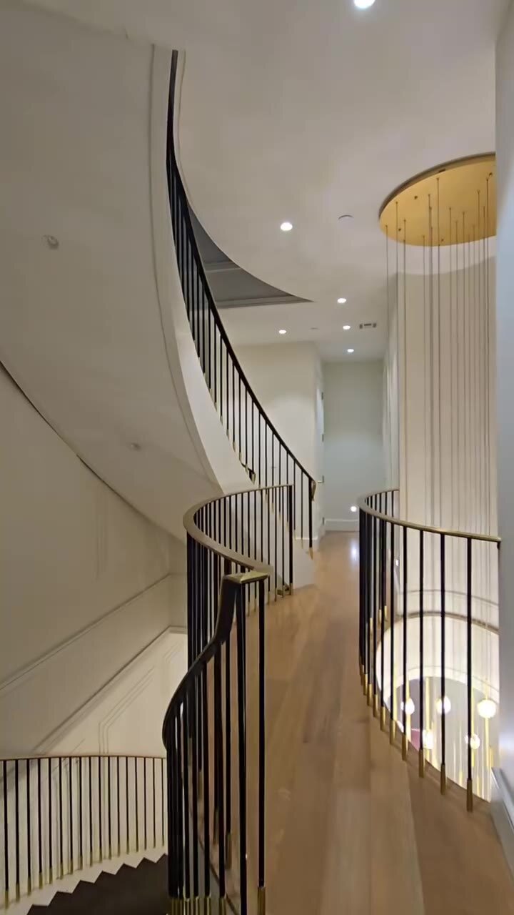 Curved staircase and upper hallway with black steel railings