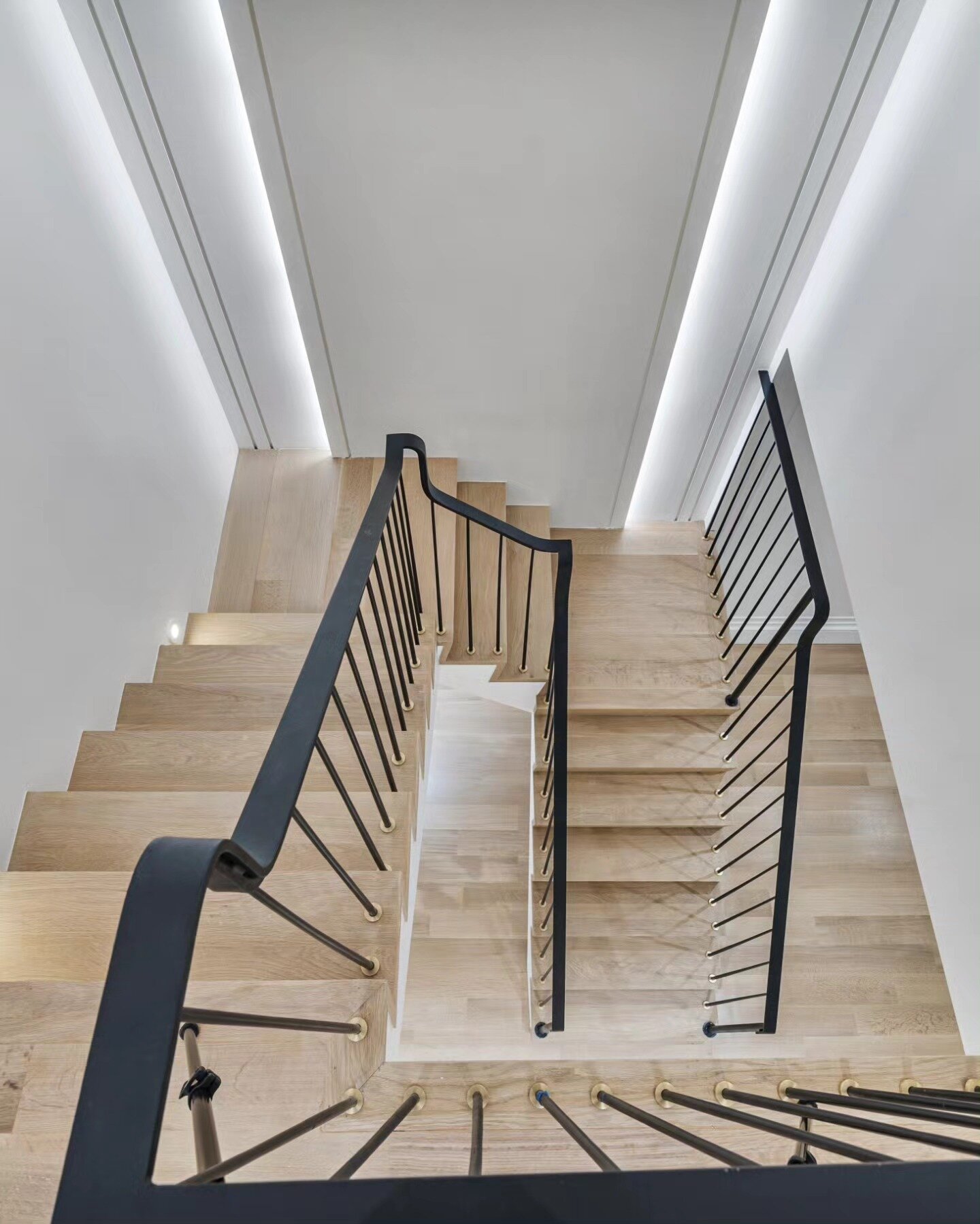 White oak staircase with black steel railings and cove lighting